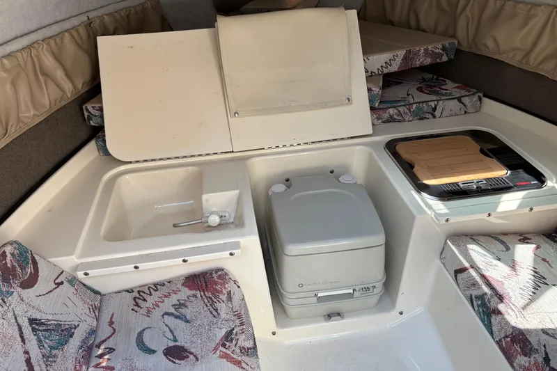 Slide: The Image of 1997 Stingray 200 CS cabin interior with sink, portable toilet, and stove. - 20