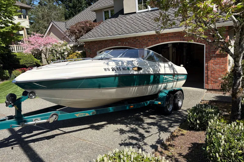 Slide: The Image of 1997 Stingray 200 CS boat on trailer in residential driveway, surrounded by greenery. - 4