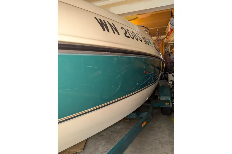 Slide: The Image of 1997 Stingray 200 CS boat in garage, teal and white hull, trailer visible. - 7