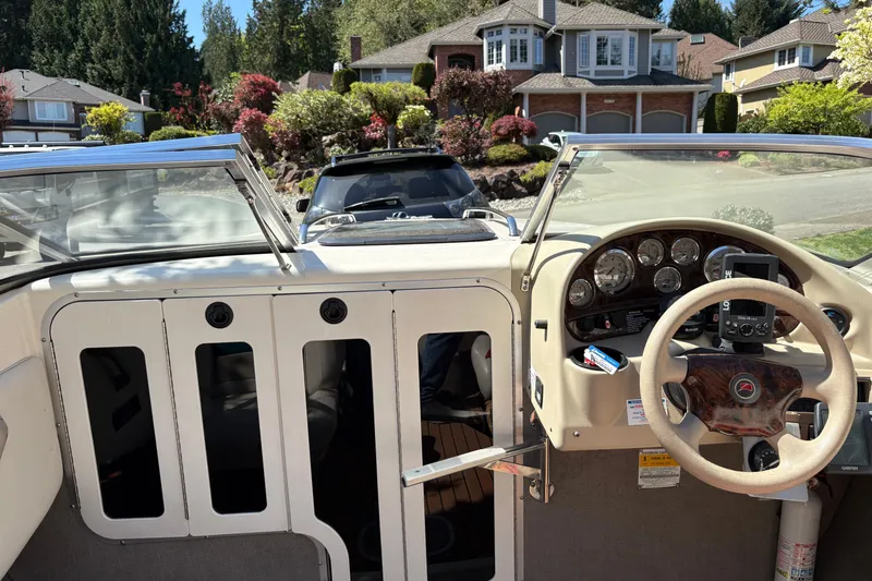 Slide: The Image of 1997 Stingray 200 CS boat interior with steering wheel and dashboard, parked in a residential area. - 8