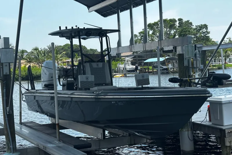 The Image of 2024 H-Craft 27 CC boat docked on a lift, surrounded by water and greenery. - 0