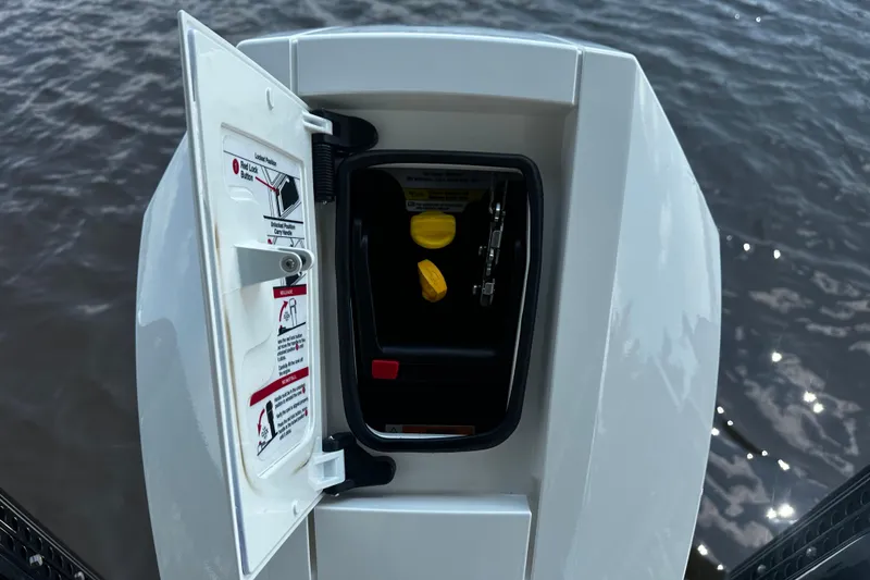 Slide: The Image of Open storage compartment on 2024 H-Craft 27 CC boat, showing safety instructions and water background. - 15