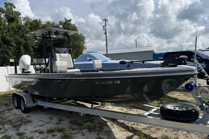 Slide: The Image of 2024 H-Craft 27 CC boat on trailer, parked outdoors under cloudy sky. - 2