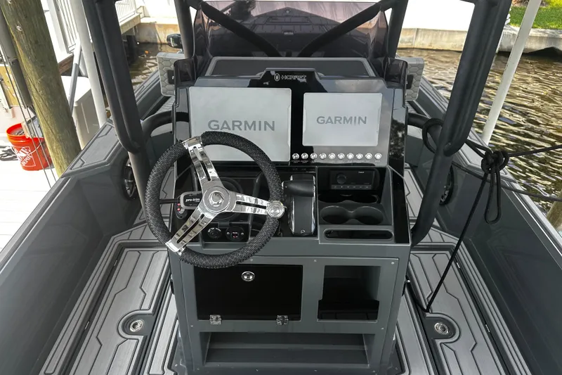 Slide: The Image of 2024 H-Craft 27 CC boat dashboard with dual Garmin displays and steering wheel. - 23