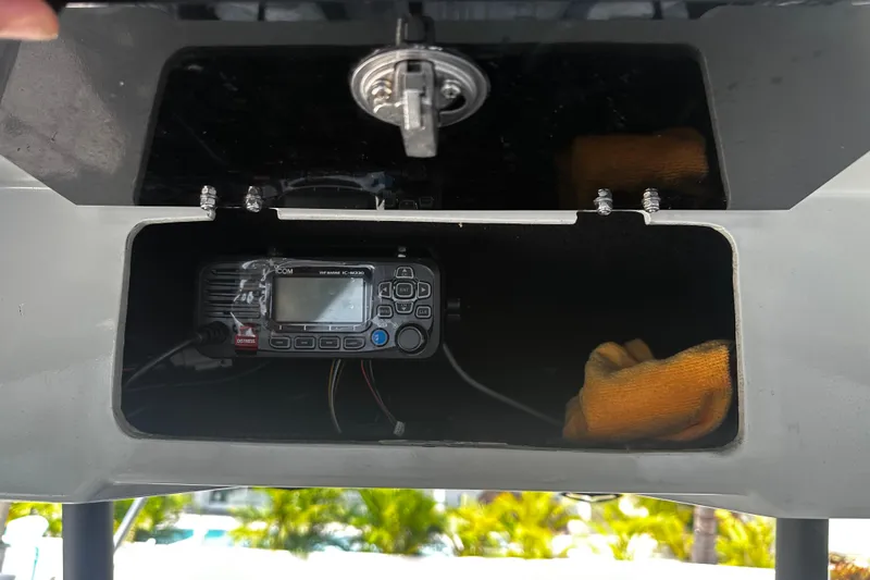 Slide: The Image of 2024 H-Craft 27 CC storage compartment with marine radio and orange cloth. - 27