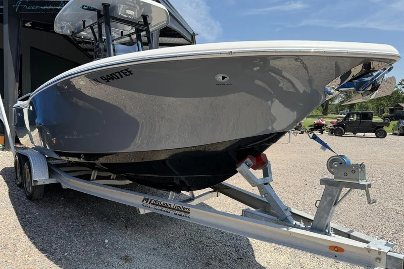 Slide: The Image of 2020 Tidewater 232 CC Adventure boat on trailer, parked outdoors under clear sky. - 2