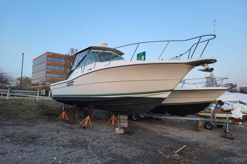 The Image of 2002 Pursuit 3000 Express boat on stands, with a building in the background. - 1