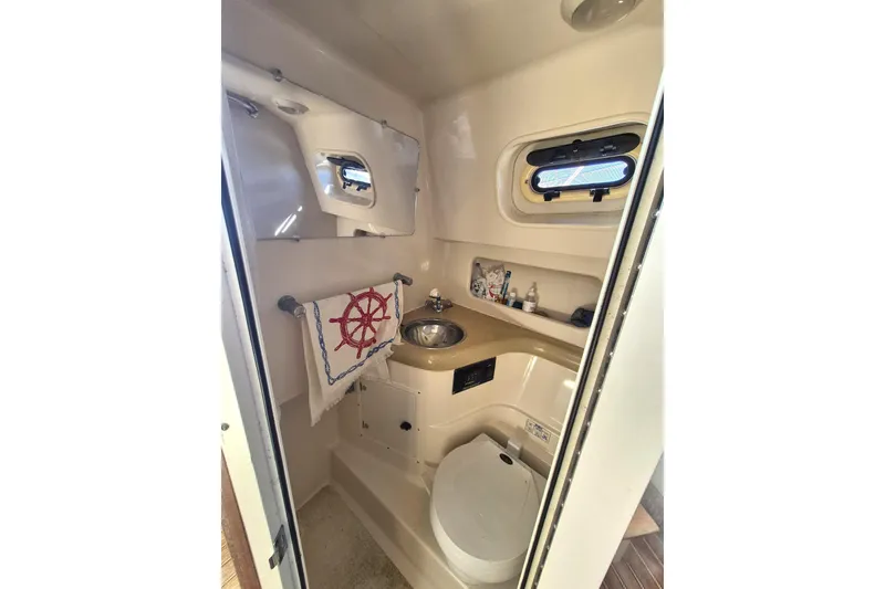 Slide: The Image of 2002 Pursuit 3000 Express boat bathroom with sink, toilet, and nautical decor. - 8
