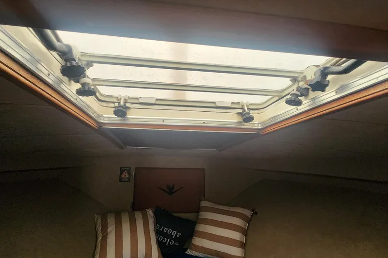 Slide: The Image of Interior cabin view of a 1985 Bertram 33 Flybridge Cruiser with skylight and striped pillows. - 20