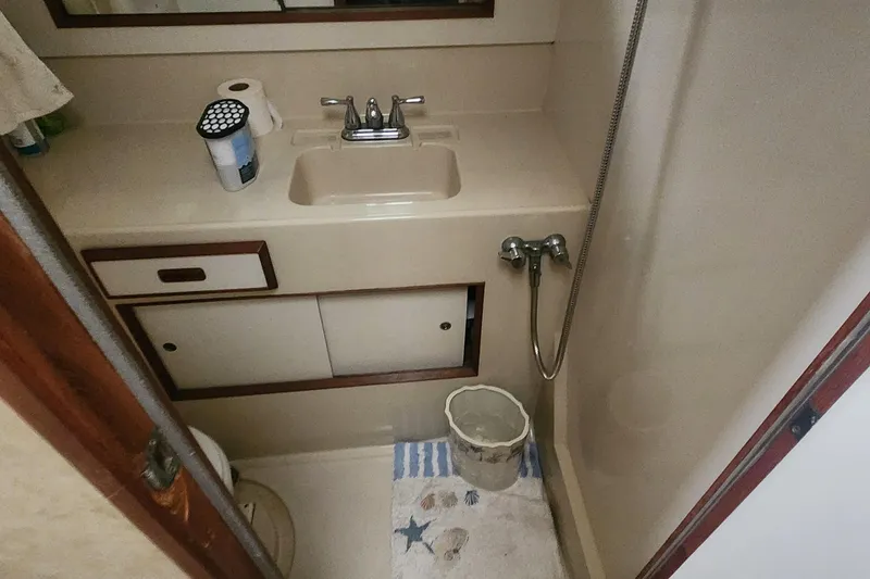 Slide: The Image of 1985 Bertram 33 Flybridge Cruiser bathroom with sink, shower, and storage cabinets. - 22