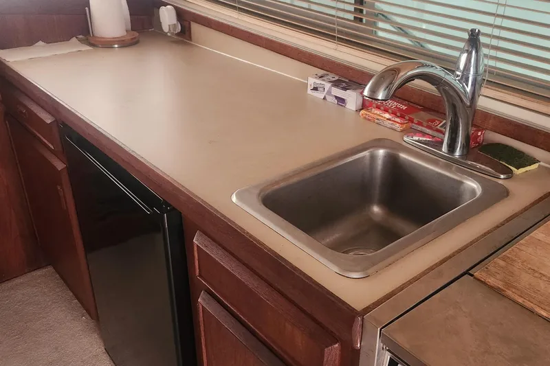 Slide: The Image of 1985 Bertram 33 Flybridge Cruiser kitchen with sink, faucet, and countertop essentials. - 26