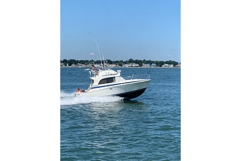 Slide: The Image of 1985 Bertram 33 Flybridge Cruiser navigating on open water under clear skies. - 4