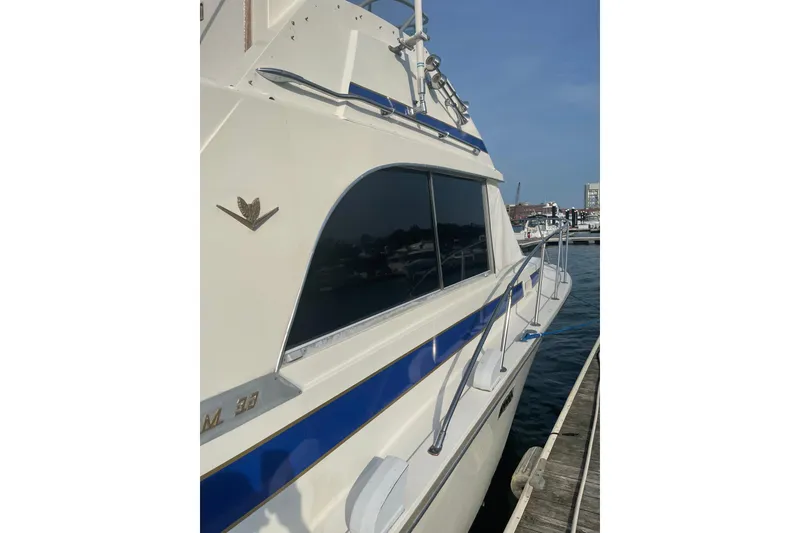 Slide: The Image of 1985 Bertram 33 Flybridge Cruiser docked, showcasing sleek design and blue accents. - 7