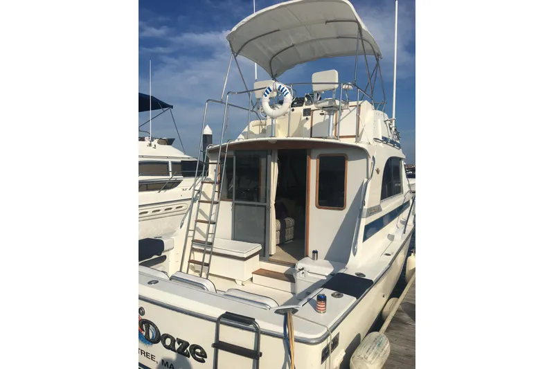 Slide: The Image of 1985 Bertram 33 Flybridge Cruiser docked, featuring a spacious deck and flybridge. - 9