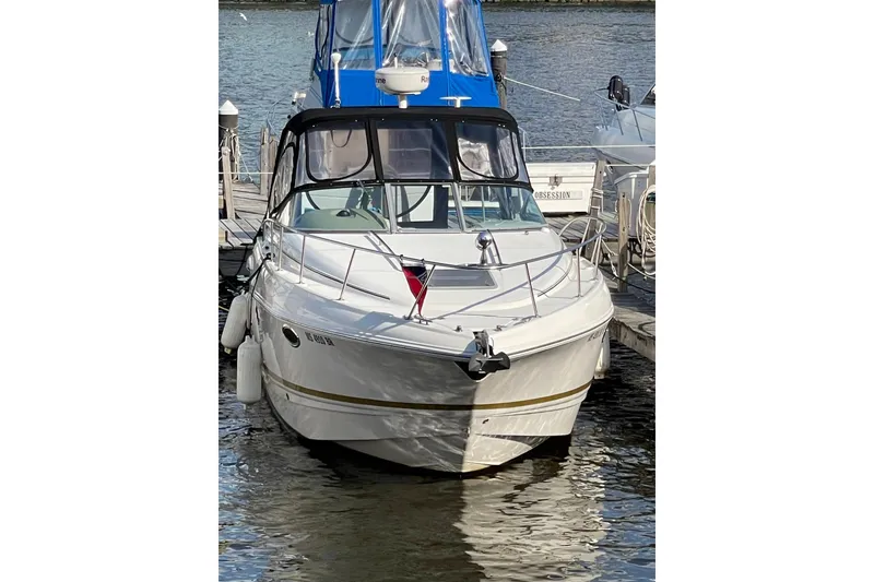 Slide: The Image of 2006 Chaparral 290 Signature boat docked at marina, featuring sleek design and blue canopy. - 2