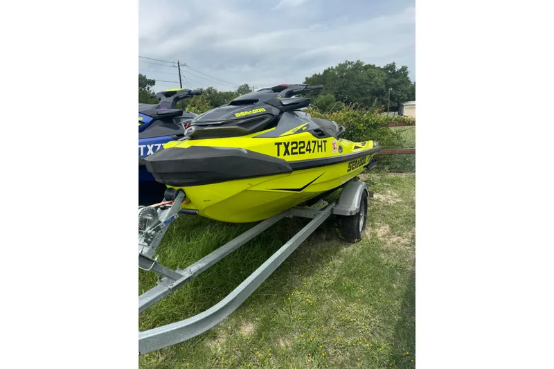 Slide: The Image of 2020 Sea-Doo RXT-X 300 jet ski on trailer, vibrant yellow, parked on grass. - 1