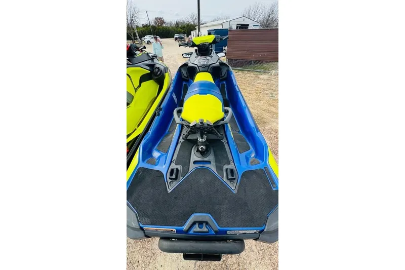 Slide: The Image of 2019 Sea-Doo Wake Pro 230 jet ski in vibrant blue and yellow, parked outdoors. - 2