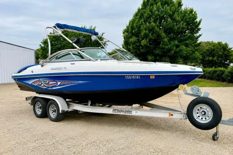 The Image of 2007 Rinker 226 Captiva Bowrider on trailer, blue and white design, parked outdoors. - 0