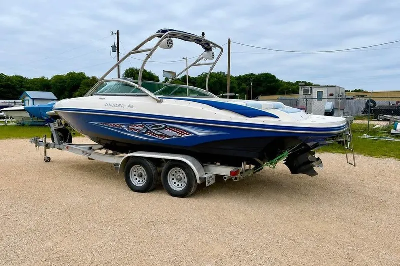 Slide: The Image of 2007 Rinker 226 Captiva Bowrider on trailer, parked outdoors, showcasing sleek design. - 2