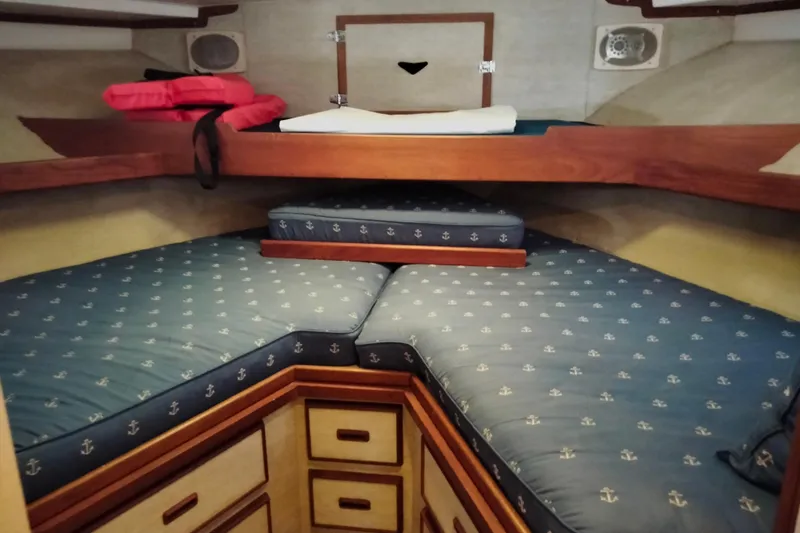 Slide: The Image of 1978 Bertram 46.6 yacht cabin with blue anchor-patterned cushions and wooden storage drawers. - 15