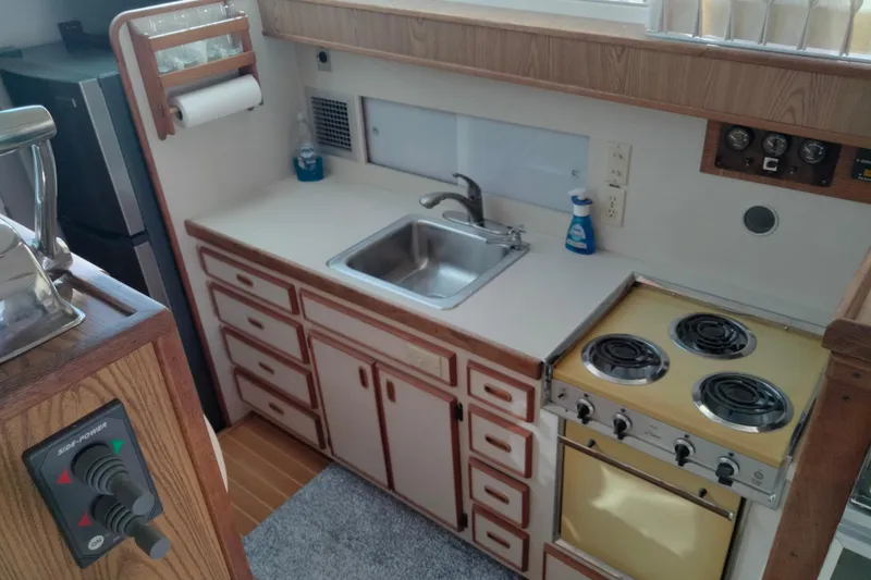 Slide: The Image of 1978 Bertram 46.6 yacht kitchen with stove, sink, and wooden cabinetry. - 20