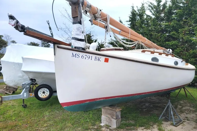 The Image of 1974 Marshall 22 Catboat on stands, with visible registration number, in a grassy area. - 0