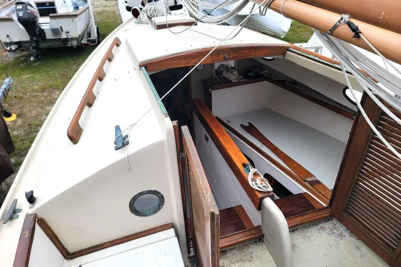 Slide: The Image of 1974 Marshall 22 Catboat interior with wooden accents and nautical ropes. - 11