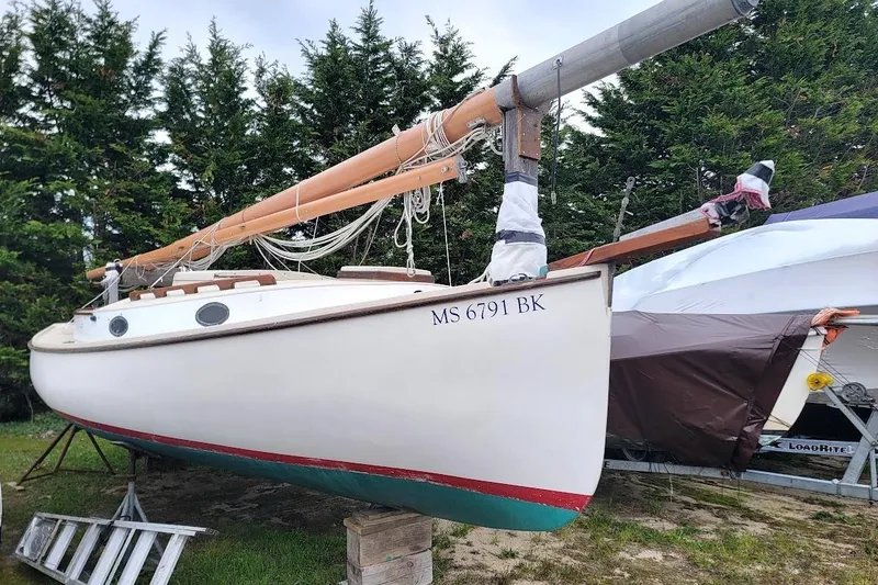 Slide: The Image of 1974 Marshall 22 Catboat on land, surrounded by trees and other boats. - 13