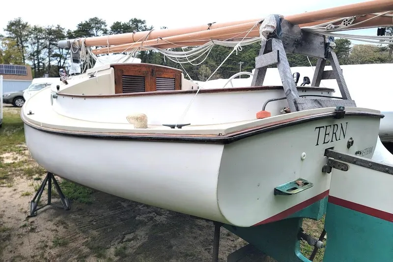 Slide: The Image of 1974 Marshall 22 Catboat "TERN" on land, showcasing classic design and wooden mast. - 19