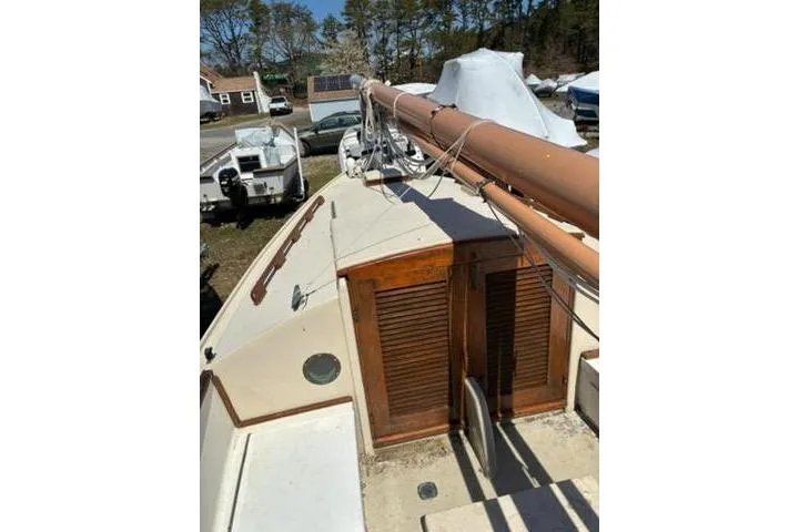Slide: The Image of 1974 Marshall 22 Catboat with wooden cabin doors and mast, docked outdoors. - 23