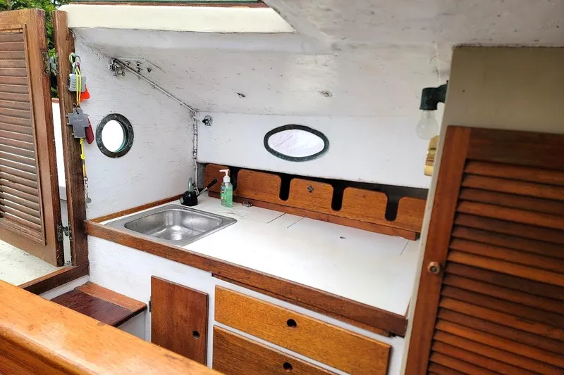 Slide: The Image of 1974 Marshall 22 Catboat interior with wooden cabinetry and compact sink area. - 3