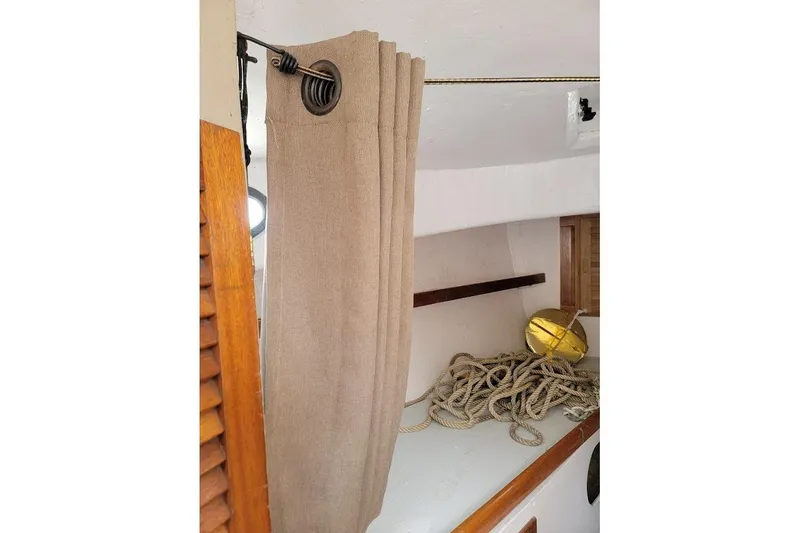 Slide: The Image of Interior of a 1974 Marshall 22 Catboat with curtain, rope, and wooden accents. - 6