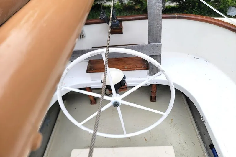 Slide: The Image of 1974 Marshall 22 Catboat cockpit with white steering wheel and wooden accents. - 9