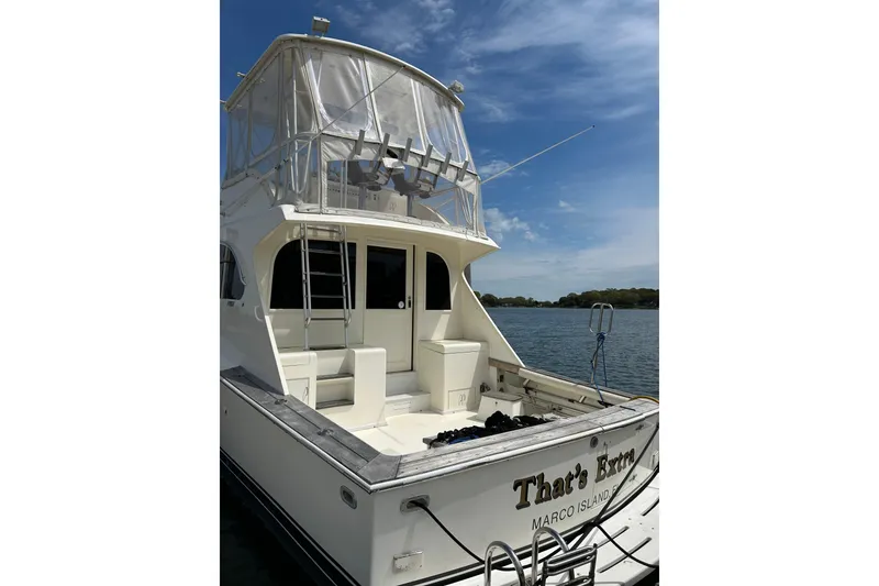 Slide: The Image of 1990 Post 46 Convertible yacht docked, featuring a spacious deck and flybridge under a clear sky. - 23