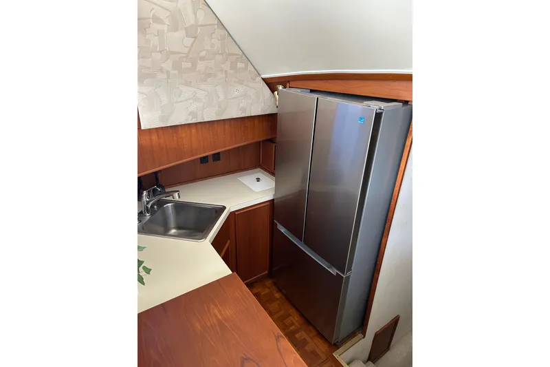 Slide: The Image of Compact kitchen area in a 1990 Post 46 Convertible boat with stainless steel fridge. - 6