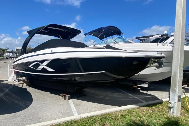 The Image of 2013 Regal 27 FasDeck RX boat in a parking lot under a clear blue sky. - 1