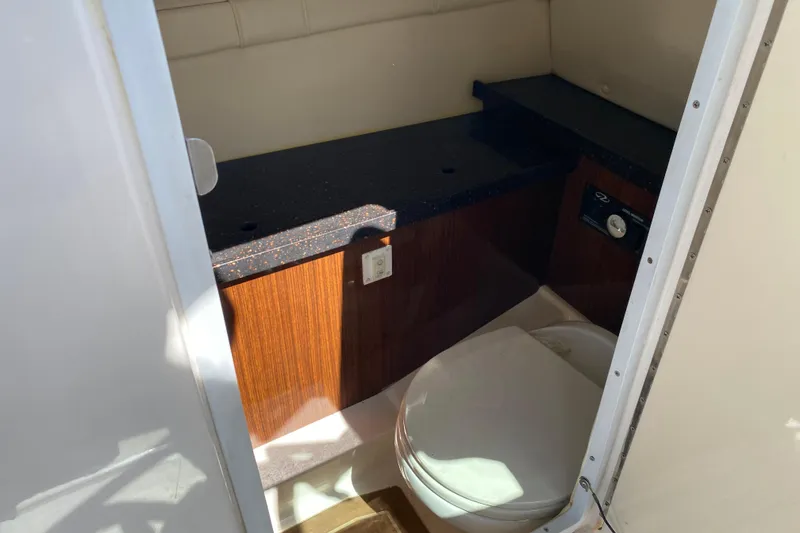 Slide: The Image of 2013 Regal 27 FasDeck RX boat interior with compact bathroom and wooden cabinetry. - 26