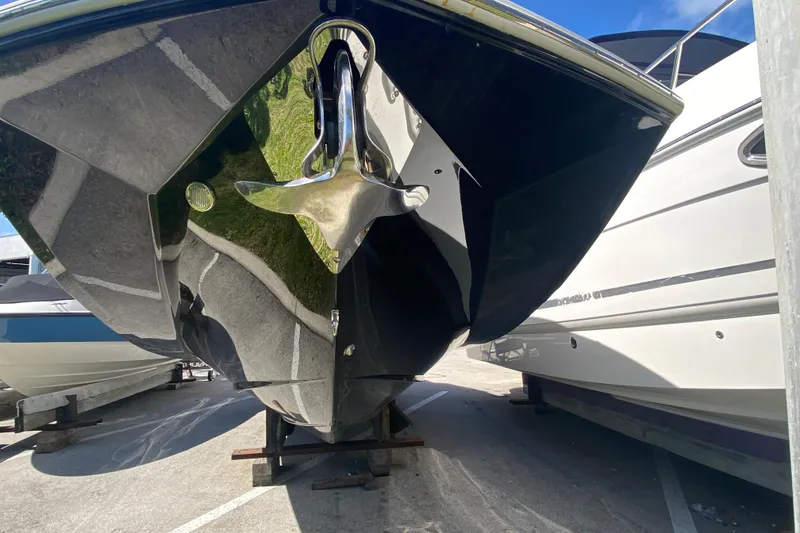 Slide: The Image of 2013 Regal 27 FasDeck RX boat, black hull, parked on a trailer in a marina. - 3