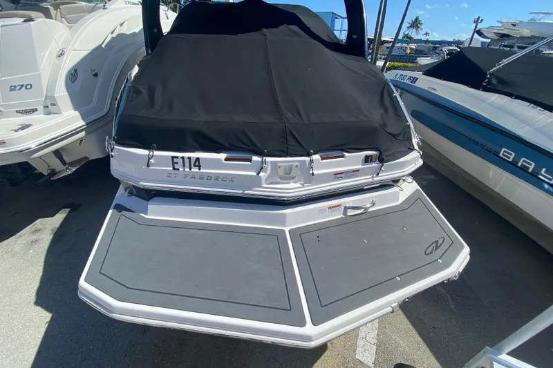 Slide: The Image of 2013 Regal 27 FasDeck RX boat with black cover, docked alongside other boats. - 4