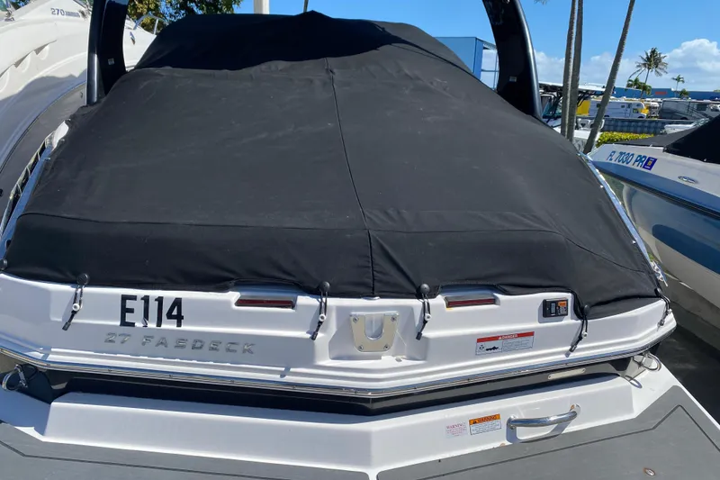 Slide: The Image of 2013 Regal 27 FasDeck RX boat with black cover, docked in a marina. - 6