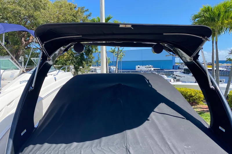 Slide: The Image of 2013 Regal 27 FasDeck RX boat with black canopy, docked near other boats. - 7