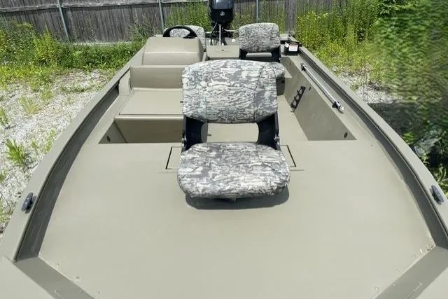 Slide: The Image of 2026 Tracker Grizzly 1754 SC boat with camo seats, parked outdoors. - 6