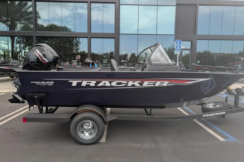 Slide: The Image of 2026 Tracker Pro Guide V-175 WT boat on trailer, parked outside modern building. - 2