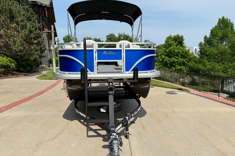 Slide: The Image of 2026 Sun Tracker Fishin' Barge 20 DLX pontoon boat on trailer, parked outdoors. - 2