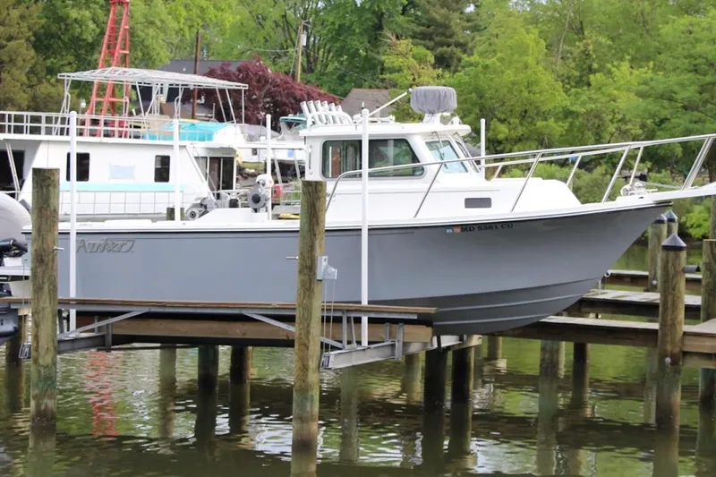 The Image of 2023 Parker 2320 Sport Cabin boat docked at a marina with lush greenery. - 1