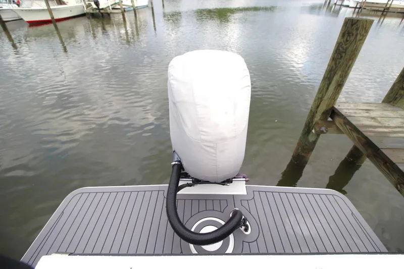 Slide: The Image of 2023 Parker 2320 Sport Cabin boat with covered outboard motor at dock. - 13