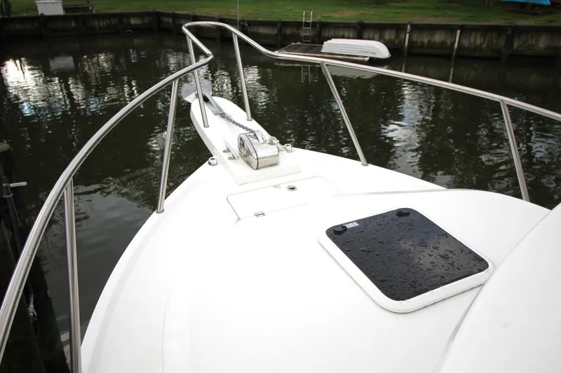 Slide: The Image of 2023 Parker 2320 Sport Cabin boat bow with railing and hatch, docked by calm water. - 9