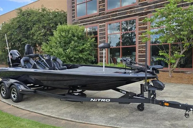 Slide: The Image of 2026 Nitro Z21 XL bass boat on trailer, parked outdoors near a building. - 5
