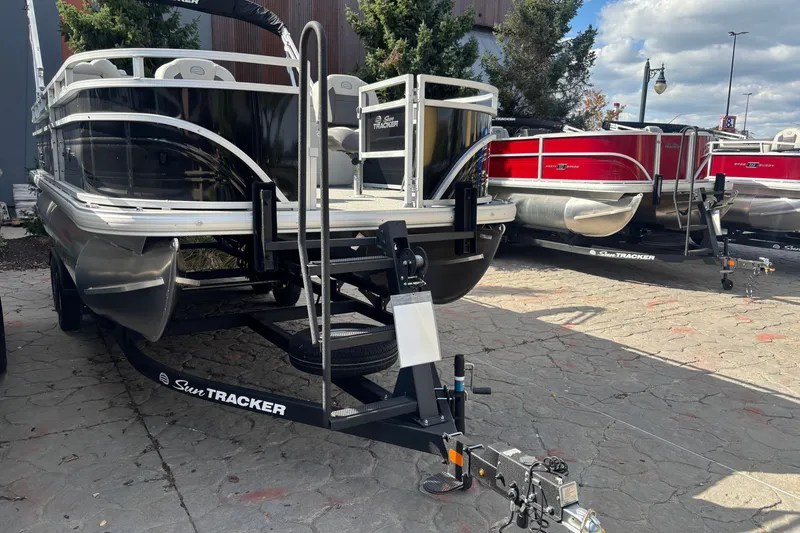 Slide: The Image of 2026 Sun Tracker Fishin' Barge 20 DLX pontoon boat on trailer, parked outdoors. - 103