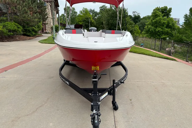 Slide: The Image of 2026 Tahoe T18 boat in red on a trailer, parked outdoors with greenery. - 2